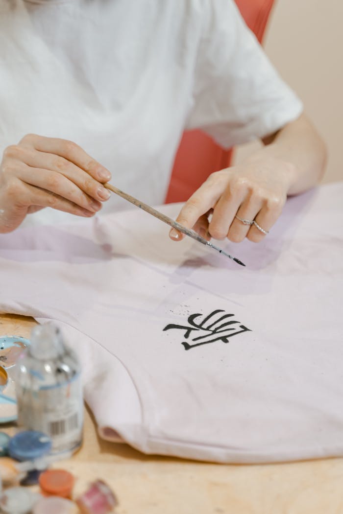 A person meticulously painting an intricate design on fabric using a brush.
